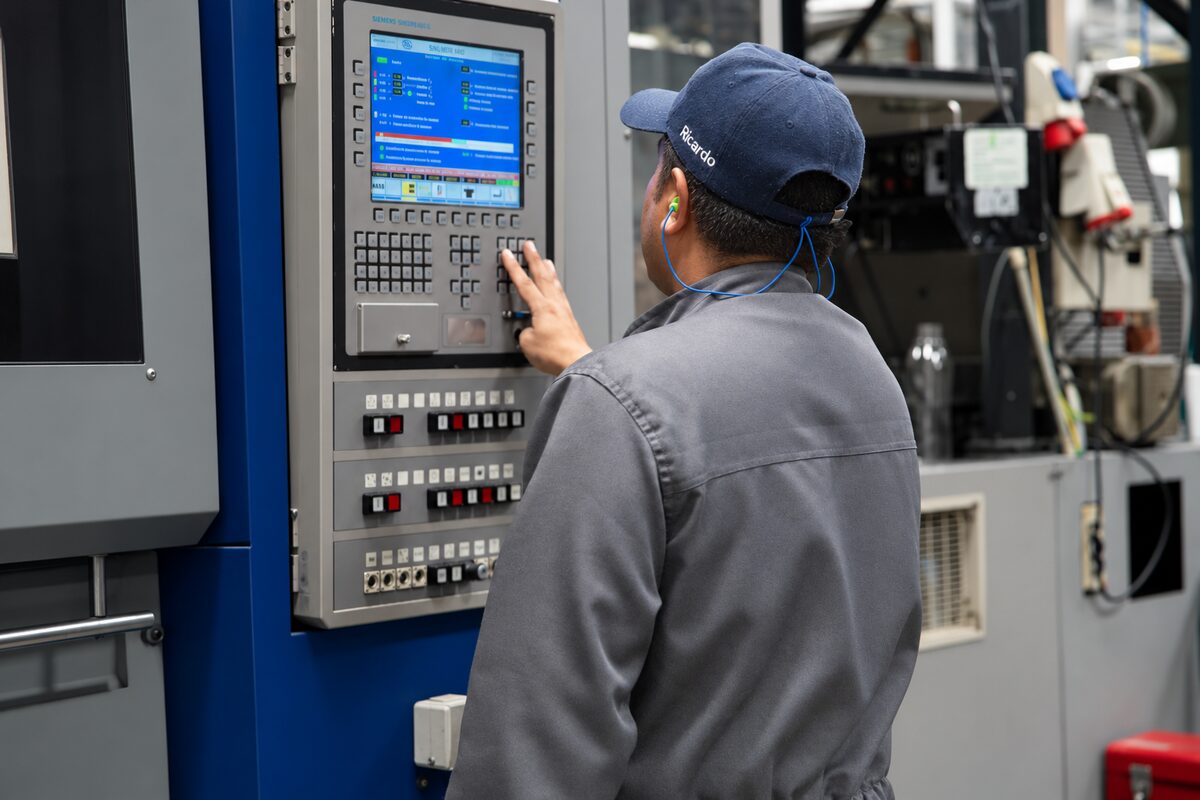 Operario ajustando el panel de control de una máquina de inyección