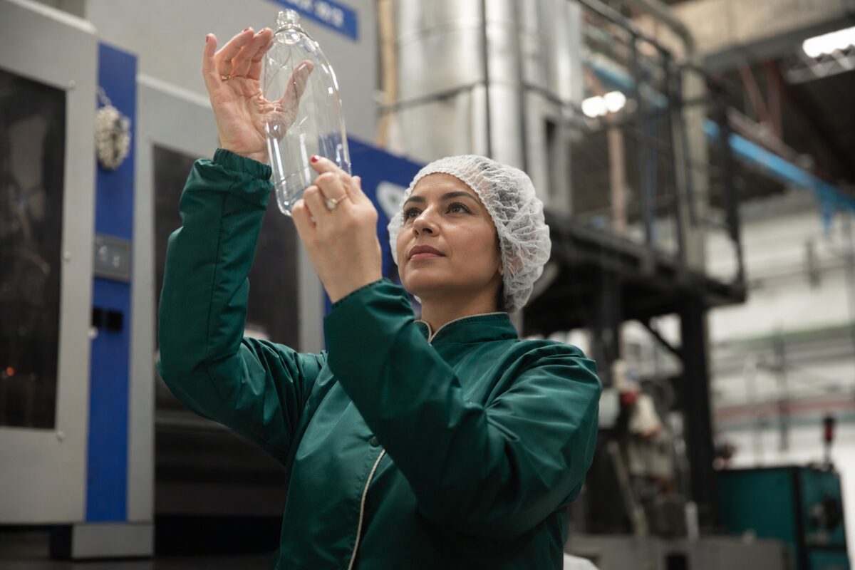 Operaria revisando una botella PET a contraluz